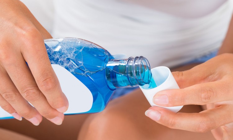 45461346 - close-up of woman hands pouring mouthwash into bottle cap