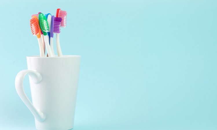 46444107 - multicolor toothbrushes in white mug, with copyspace